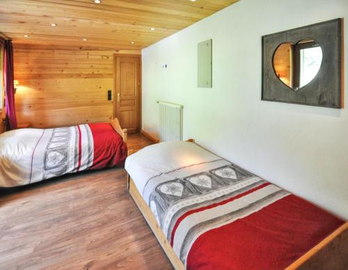 Dos camas en una habitación con paredes de madera. en Appartement lumineux à La Chapelle-d'Abondance, vue montagne., en La Chapelle-dʼAbondance