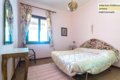 a bedroom with a bed and a table and a window at Villa Ylenia Marsala in Marsala