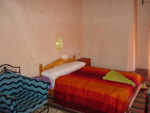 a bedroom with two beds with colorful sheets at Kasbah Ait Kassi in Boumalne