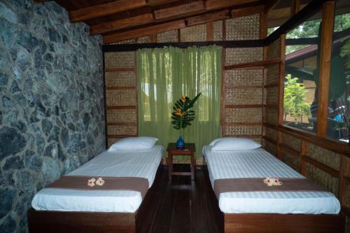 two beds in a room with a stone wall at Kiao Beach in Anepahan
