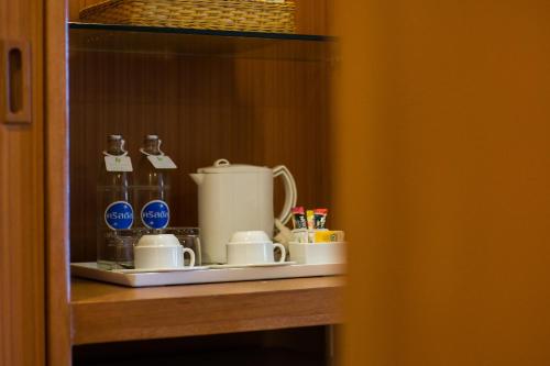 a shelf with a coffee pot and cups on it at Bangkok Palace Hotel in Bangkok