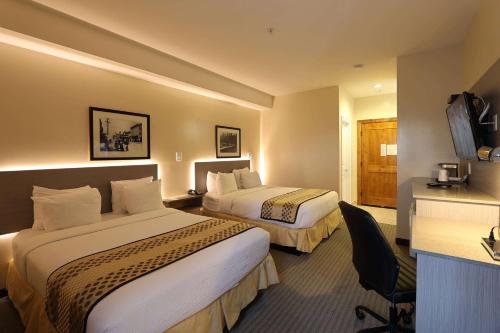 a hotel room with two beds and a desk at Days Inn by Wyndham Surrey in Surrey
