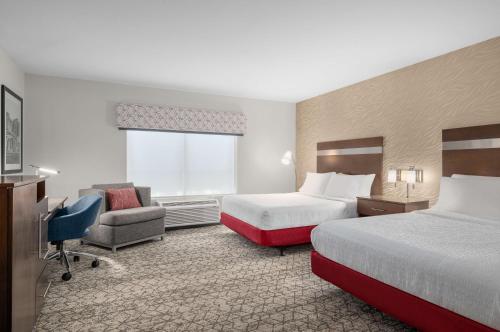 a hotel room with two beds and a chair at Hampton Inn Atlanta McDonough in McDonough