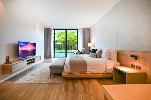 a bedroom with a large bed and a tv at Villa De Time - The Luxury Private Pool Villa in Pattaya South