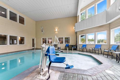 a swimming pool with blue chairs and chairs around it at Comfort Inn Traverse City in Traverse City