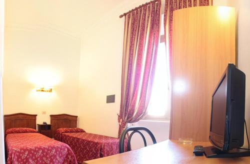 a room with two beds and a tv and a window at Hotel Euro Quiris in Rome