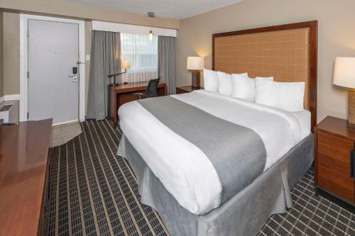 a hotel room with a large bed and a desk at Clarion Pointe in Medicine Hat