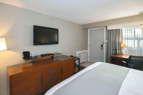 a hotel room with a bed and a desk and a television at Clarion Pointe in Medicine Hat