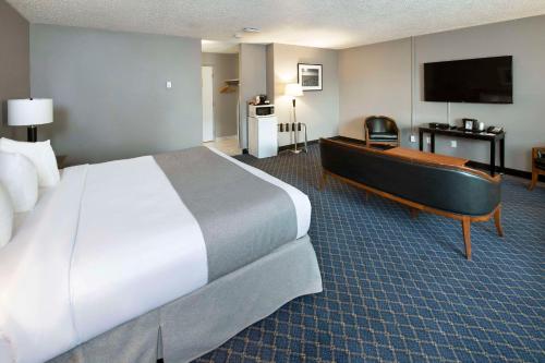 a hotel room with a bed and a flat screen tv at Clarion Pointe in Medicine Hat