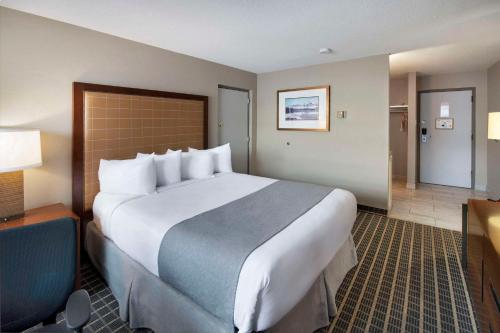 a hotel room with a large bed and a desk at Clarion Pointe in Medicine Hat