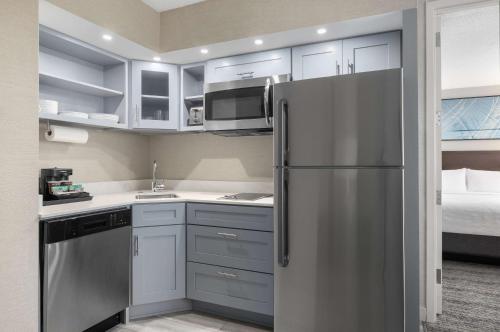 a kitchen with a stainless steel refrigerator next to a bed at Homewood Suites By Hilton Downers Grove Chicago, Il in Downers Grove