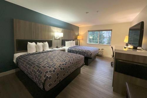 a hotel room with two beds and a flat screen tv at Baymont by Wyndham Kent - Seattle in Kent