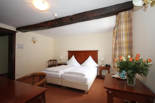 a bedroom with a white bed and a table and chairs at Hotel Drei Linden in Lünen