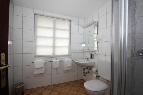 a white bathroom with a toilet and a sink at Hotel Drei Linden in Lünen