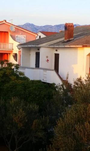 a white house with mountains in the background at Stela 1 in Povljana