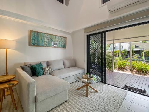 a living room with a couch and a sliding glass door at Canopy Chalet 10 in Nelly Bay