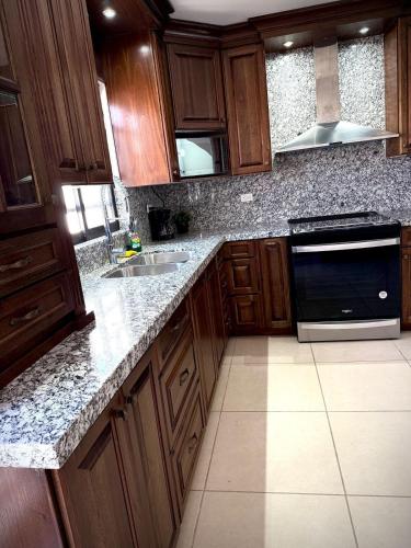 a kitchen with wooden cabinets and granite counter tops at Casa Cedro Azul in Hermosillo