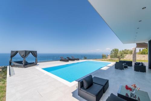 a swimming pool with furniture and the ocean in the background at Zenvillas in Lefkada Town