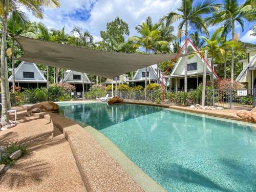 a swimming pool with a hammock in front of some houses at Canopy Chalet 10 in Nelly Bay