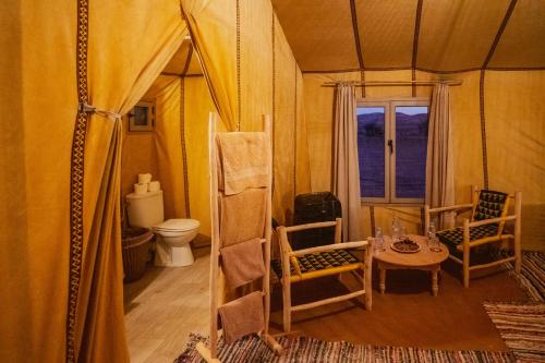 a room with a tent with a table and chairs at Auberge Bivouac La Belle Etoile in Merzouga