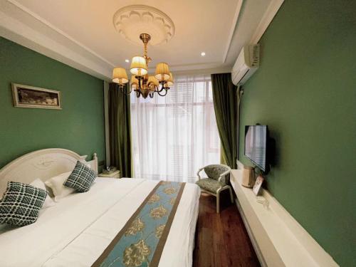 a bedroom with green walls and a bed with a chandelier at 张家界小情调精品民宿 in Zhangjiajie