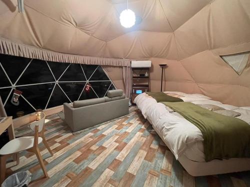 a bedroom with a tent with a bed and a chair at 伊豆Cocoグランピングリゾート in Ito