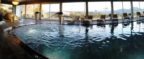 einen Pool in einem Hotel mit Stühlen und einem Tisch in der Unterkunft Hotel Post Victoria in Oberbozen