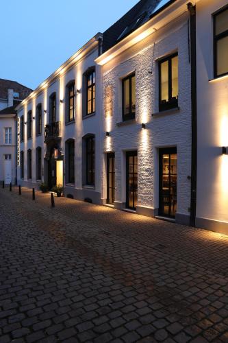 a row of white buildings on a cobblestone street at Hotel Hof van Aragon in Lier