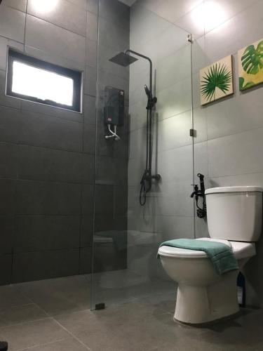 a bathroom with a toilet and a glass shower at Villa Beau Rivage in Bachok