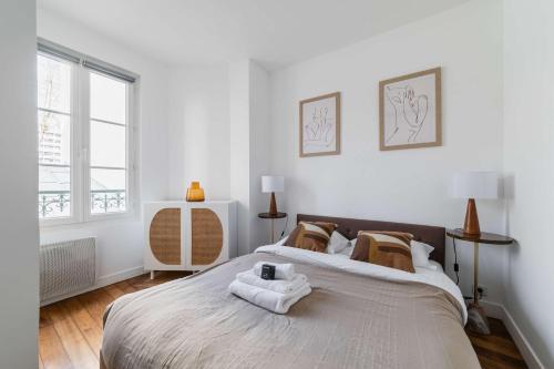 une chambre avec un grand lit avec des serviettes dessus dans l'établissement Appartement Gare de reuilly - Paris 12 - 4p - FLAT-GUEST, à Paris