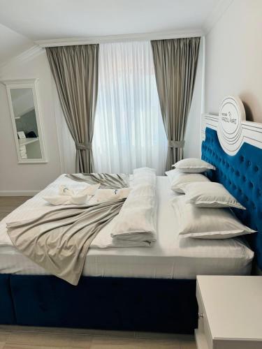 a large bed with a blue headboard and pillows at Pensiunea Paradisul Mării in Sulina