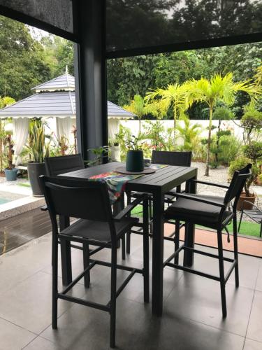 a dining room table and chairs with a view of a yard at Villa Beau Rivage in Bachok