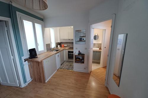 une cuisine avec des armoires blanches et un plancher en bois dans l'établissement Cosy apartment with all amenities, à Paris