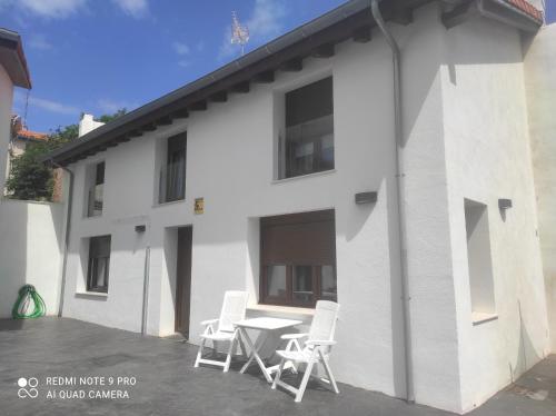 ein weißes Gebäude mit Stühlen und einem Tisch davor in der Unterkunft CASA EN EL CENTRO HISTÓRICO DE CASTRO URDIALES in Castro-Urdiales