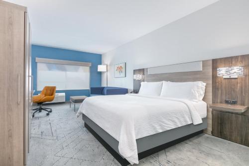 a hotel room with a large bed and a chair at HOLIDAY INN EXPRESS & SUITES DALLAS PLANO NORTH by IHG in Plano