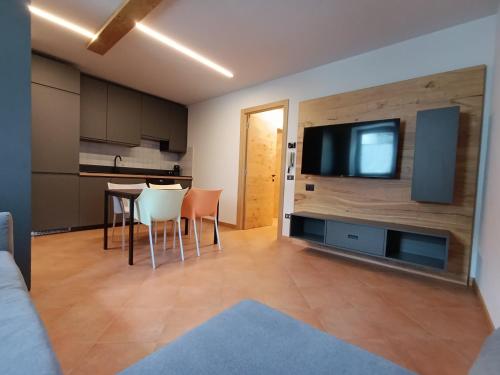ein Wohnzimmer mit einem Tisch und einem TV an der Wand in der Unterkunft Villa Emma in Ponte di Legno