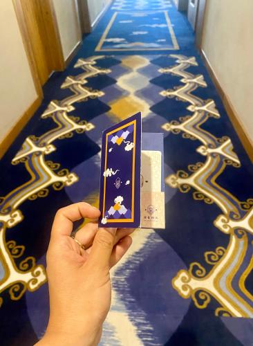 a person holding up a card on a carpet at Hotel Rewa Ladakh in Leh