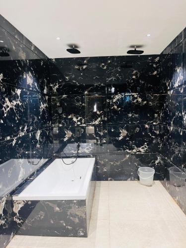 a black tiled bathroom with a tub and a sink at Taj Dream A Luxury Hotel - Agra in Agra