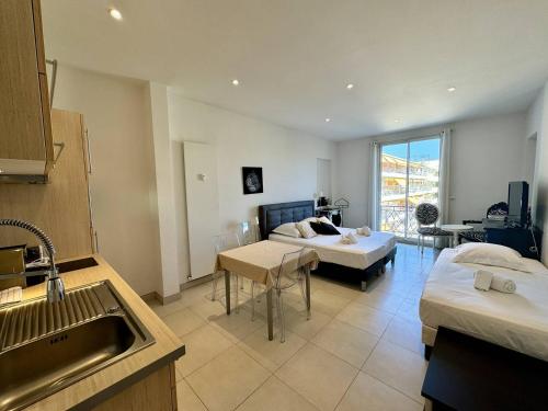 une chambre avec deux lits et une cuisine avec un évier dans l'établissement Cannes La Croisette - Joli studio au calme coté jardin, à Cannes