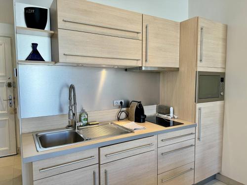 une cuisine avec des armoires en bois et un évier dans l'établissement Cannes La Croisette - Joli studio au calme coté jardin, à Cannes