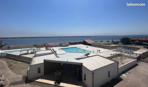 - un bâtiment avec une piscine à côté de l'eau dans l'établissement Le Barcarès - Belle vue sur lac - Piscine chauffée, au Barcarès