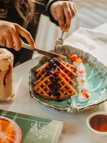 a person is eating waffles on a plate at Holiday Inn Chandigarh Zirakpur by IHG in Chandīgarh