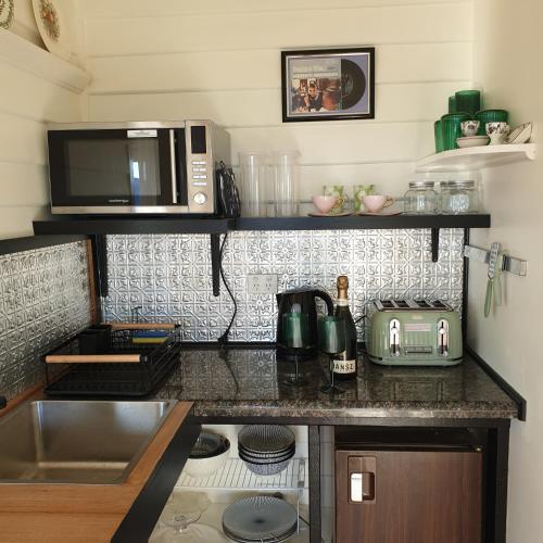 a kitchen counter with a microwave and a sink at Huon Belle Homestead in Waterloo
