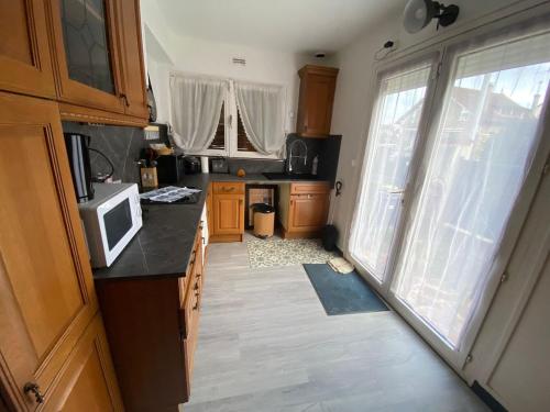 a kitchen with wooden cabinets and a microwave at Charmante maison individuelle in Orly