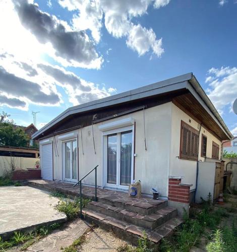 Une petite maison blanche avec des escaliers en face de celle-ci dans l'établissement Charmante maison individuelle, à Orly
