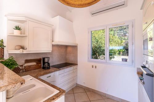 une cuisine avec un évier et une fenêtre dans l'établissement Casa Vinti - Vue mer et montagne climatisé, à Porticcio