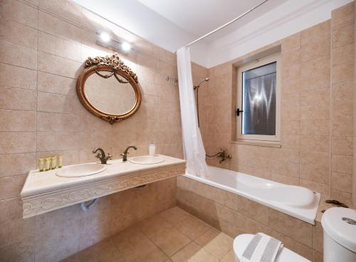 a bathroom with a sink and a tub and a mirror at Villa Galini in Nydri
