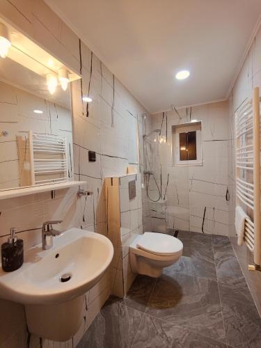 a white bathroom with a sink and a toilet at Ferien Chalet in Buşteni