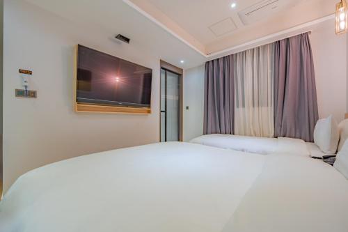 a hotel room with two beds and a flat screen tv at GijangYeonhwari No,25 Hotel in Busan