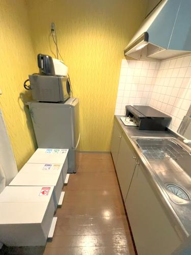 a small kitchen with a sink and a microwave at グランディオーソ中野富士見町 in Tokyo